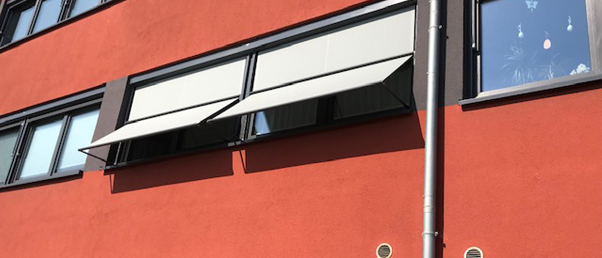Herkenhoff Referenzen Sonnenschutz dunkle Fensterrahmen neben rotem Putz